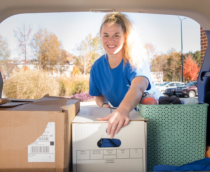 Girl putting box in car